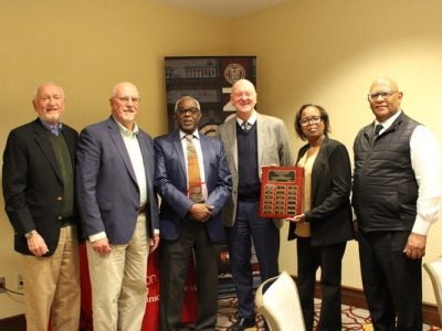 A group of six people hold an award plaque.