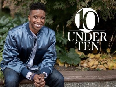 Aaron Sebron sitting on a bench, leaning forward and smiling, with a green chrub in the background and a graphic treatment of "10 Under 10" overlaid on the side of the photo