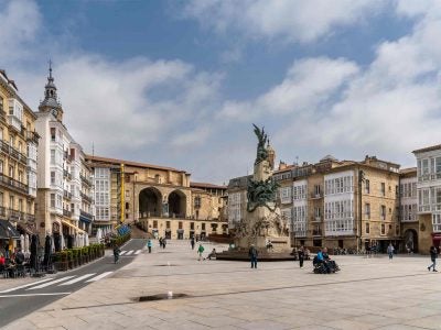 photo of a European city plaza wtih a monument in the middle and surrounded by 3-5-story buildings with retail stories on their ground floors.