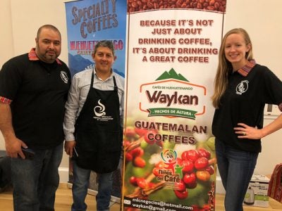 Abner Argueta and Manrique Lopez with Maggie in front of their event sign