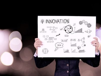 Photo of a woman holding a sign that says innovation with illustrated charts