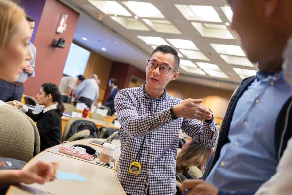Cornell MBA students in casual attire collaborate in a brightly lit lecture hall
