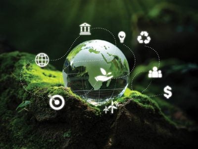 Photo of a crystal globe on a bed of moss overlaid with ESG icons for Environment, Social, and Governance, as well as world sustainable environment concepts/icons.