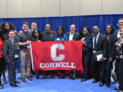 A group standing with a Cornell banner