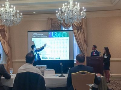 Photo of three students presenting in front of a screen