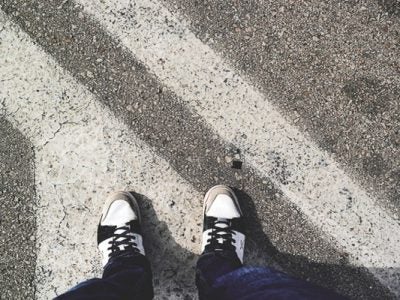 Photo of a persons shoes walking on the road