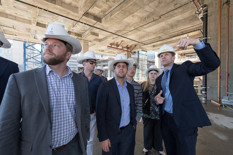 Photo of men wearing hard hats and cowboy hats at a construction site