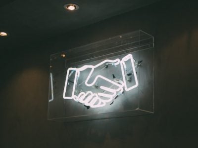 Image of neon sign depicting two hands shaking