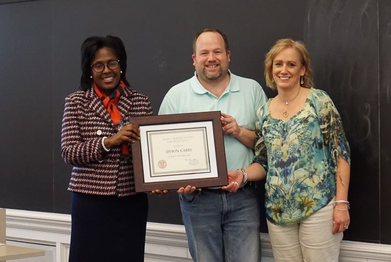 Photo of Lynn and two staff members holding a certificate