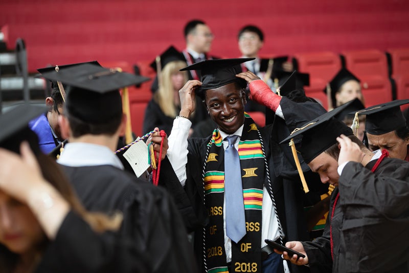 Photo of a graduate positioning his cap