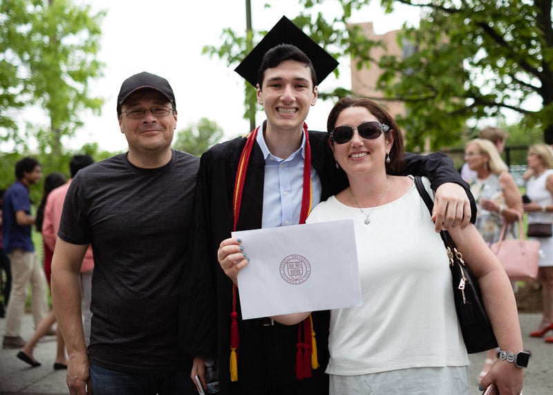 Photo of a graduate holding his certificate with his family