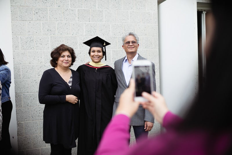 Photo of a person taking a photo of a graduate and his family