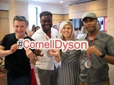 Alumni smile holding a #CornellDyson sign
