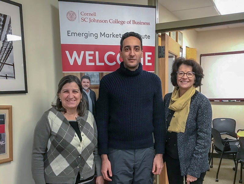 Three people stand in front of the Emerging Markets sign