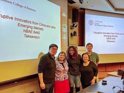 Executive MBA students and senior lecturer Casanova stand in front of a presentation board for the class