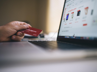 A laptop computer and a hand holding a credit card