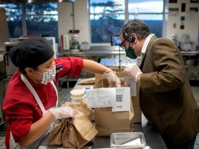 Two Statler Hall employees work together to pack to-go orders from Establishment, a student-run restaurant.