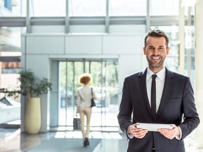 Photo of a man standing in a lobby holding a tablet