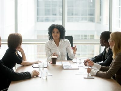 Female boss leading diverse corporate team meeting in boardroom