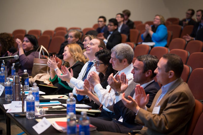 Photo of faculty clapping in an auditorium after a presentation