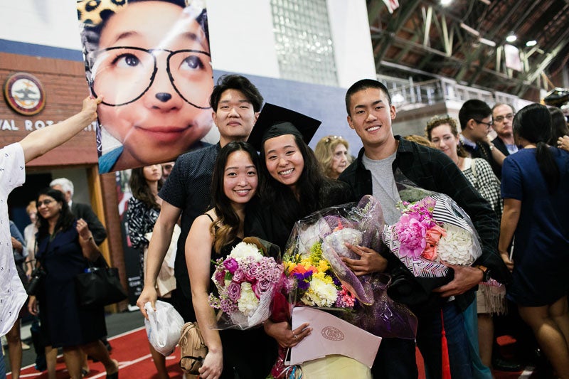 Photo of a graduate and their family holding flowers