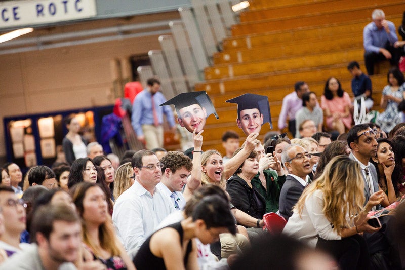 Photo of a family holding cardboard cutout heads of their graduate