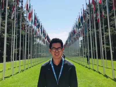 Feam standing among two rows of flags outdoors