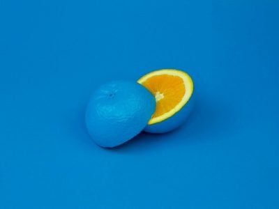 A blue orange cut in half to show normal orange inside