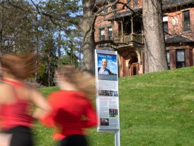 runners move by Signage at the corner of Feeney Way and Tower Road.