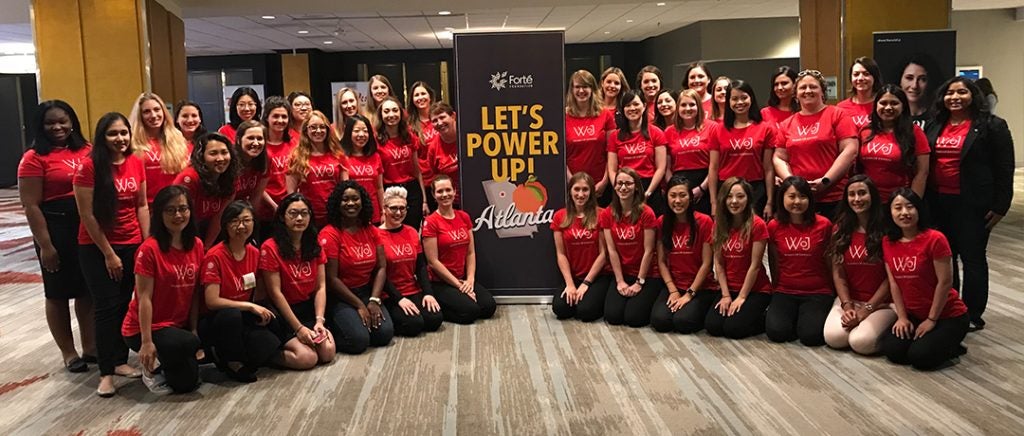 A large group of women with a sign that says "Let's Power Up."