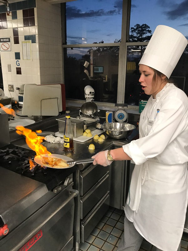 Photo of a student cooking with fire on a cooktop