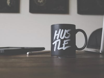 Coffee mug on a desk that says "hustle"