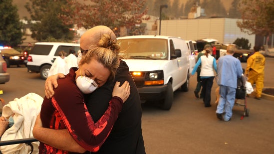 Coworkers hugging among smoke and rescue vehicles