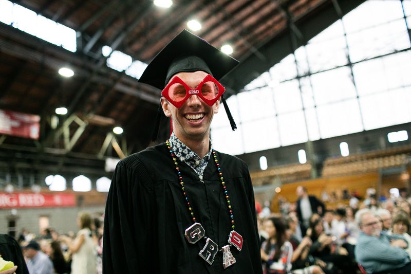 Photo of a graduate wearing a "grad" pair of glasses and necklance