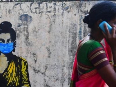 A wall painting showing Indian women using a mask to protect from Covad-19, and an Indian Women walking talking in the phone