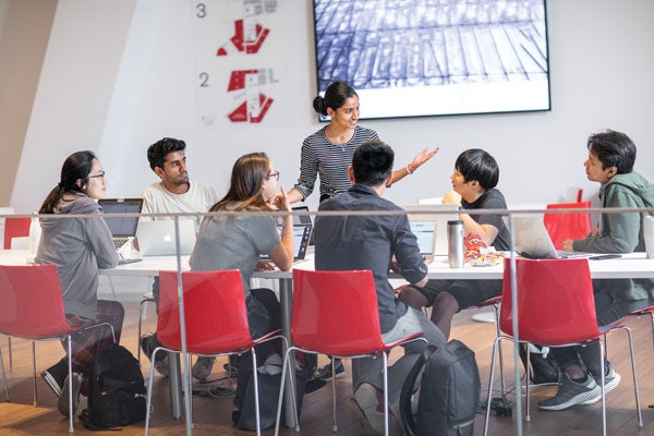 A young woman leads classmates in a bright contemporary presentation space at Tata Innovation Center at Cornell Tech's Roosevelt Island campus