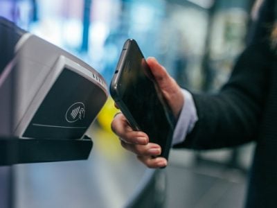 A person uses a cell phone at a payment terminal to make a wireless payment.