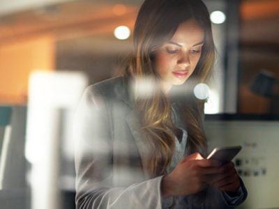 An employee checks her smart phone for employer updates.