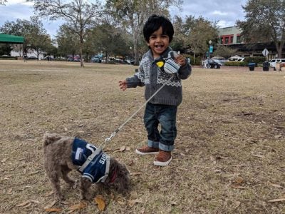 Photo of Karthika's son walking a dog and smiling