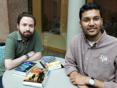 David and Nitin sit with Larson books in Sage Hall