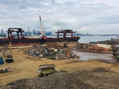 Scrap metal pile with machines and the NYC skyline