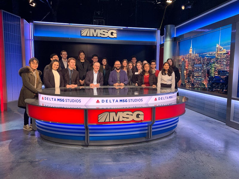 Students standing around the MSG desk in the studio