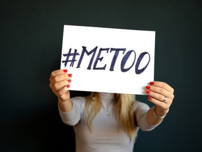 Photo of a woman holding a sign that says #METOO