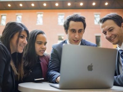 MPS students in discussion looking at a laptop