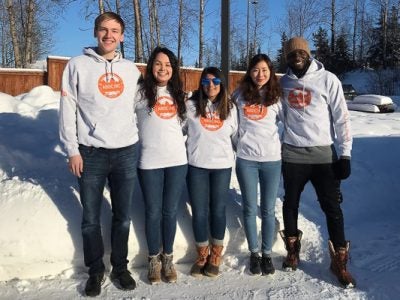 Group of five students stands in the snow