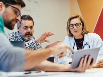 Healthcare professionals gathered around a tablet and table