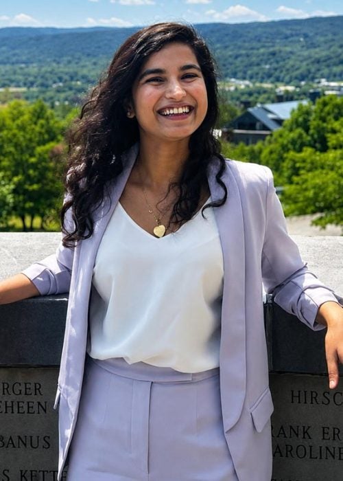A businesswoman smiles with her arms up on an engraved stone wall