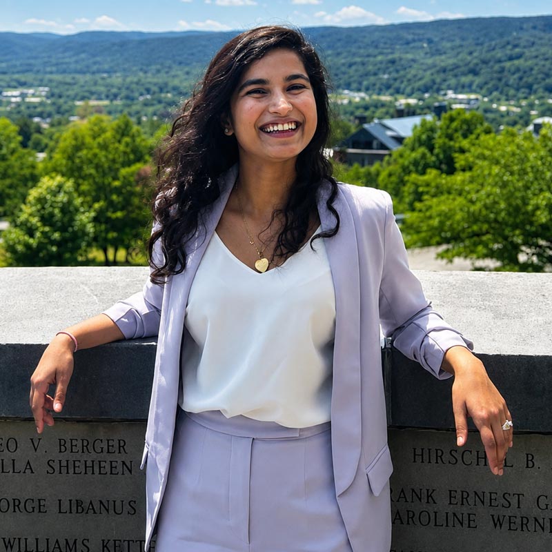 A businesswoman smiles with her arms up on an engraved stone wall