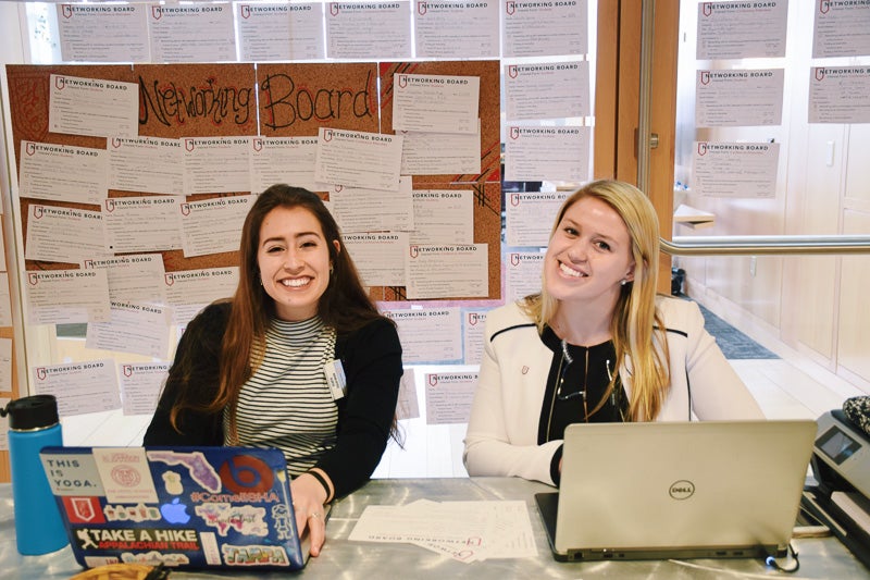 Two students sit in front of a full bulletin board