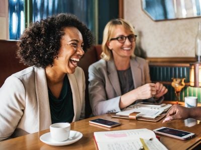 Two women laughing over coffee